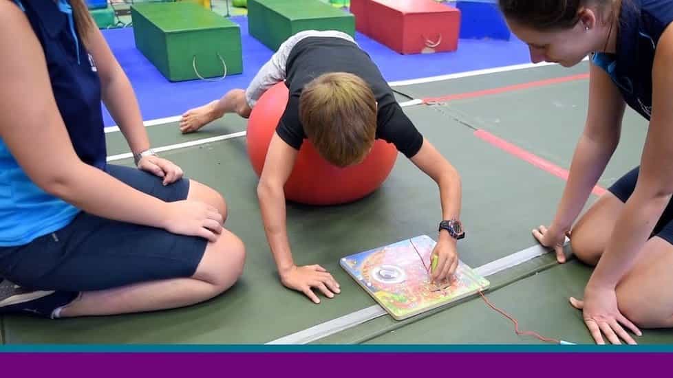 Boy painting while balancing on exercise ball.